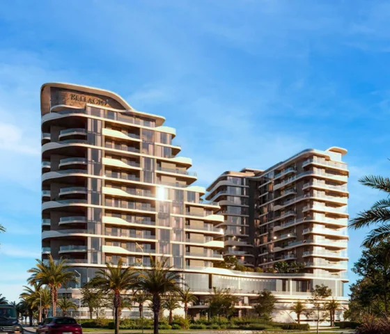 A modern residential building with a curved, layered facade, surrounded by palm trees under a clear sky.