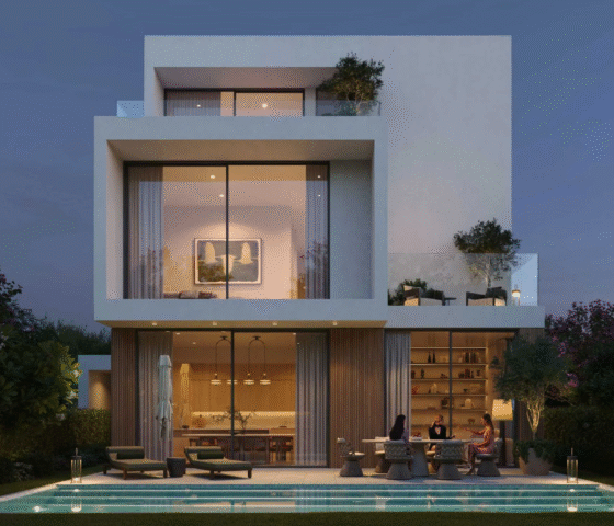 Rear view of a modern villa at Chevalia Estate 2, showing the backyard with a swimming pool and illuminated patio area at dusk.