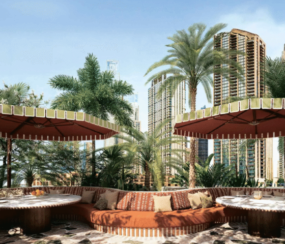 Outdoor lounge and seating area with lush greenery and a view of the Dubai cityscape .