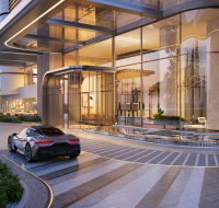 Architectural rendering of a grand building lobby entrance with reflective glass and a sleek driveway at sunset.