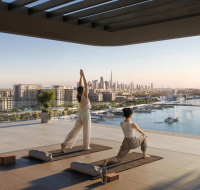 A wellness amenity at AUREA, showing residents practicing yoga on the terrace with a skyline view.