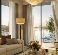 Modern apartment living room with a neutral sofa and floor-to-ceiling windows overlooking the waterfront.