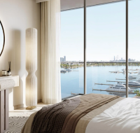 A bright bedroom with floor-to-ceiling windows and a panoramic view of luxury yachts.