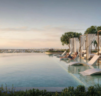 Stylish residential complex featuring a pool, outdoor seating, lush greenery, and a high-rise skyline in the background.