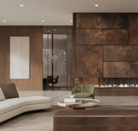 A contemporary lounge or lobby area with a large, curved sofa, a striking textured wall with a built-in fireplace, and a view into a modern office space.