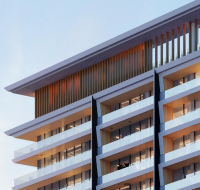 Modern multi-story building with staggered balconies, glass railings, and vertical wood slats on the upper level, viewed from a low angle against a clear sky.