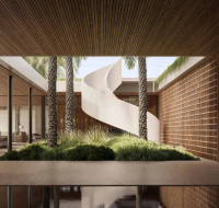 An elegant building lobby with a distinctive winding staircase, large pillars, and natural greenery.