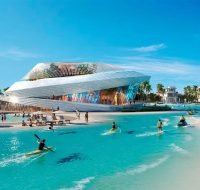 Tropical community beach area with turquoise water, palm trees, and a distinctive piece of architectural art.