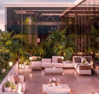 Rooftop terrace with lounge seating and lush greenery overlooking the city skyline and a lagoon