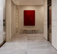 Modern residential lobby hallway with marble flooring, an elevator, and a striking red abstract painting.