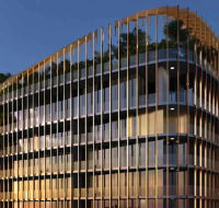 Modern residential building with curved facade, vertical architectural fins, wraparound balconies, and integrated greenery under a clear evening sky .