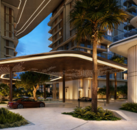 A luxury residential building entrance with a modern, curved canopy and lush landscaping at dusk.