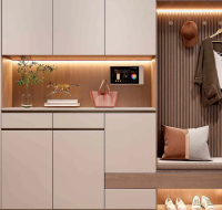 A modern entryway with a built-in cabinet, smart home tablet, coat hooks, and shoe storage