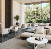 Elegant lobby with floor-to-ceiling windows, cream sofas, marble coffee table, and greenery outside