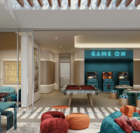 Modern indoor game room with pool table, arcade machines, lounge seating, and bookshelf under natural skylight.