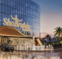 A grand luxury commercial building entrance with a curved, illuminated canopy and a prominent water fountain.
