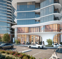 Contemporary glass-fronted building with curved balconies, a stylish entrance, and cars parked in front.