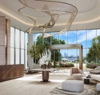 Grand residential lobby featuring an artistic, sculptural chandelier, a curved reception desk, and large windows with greenery.